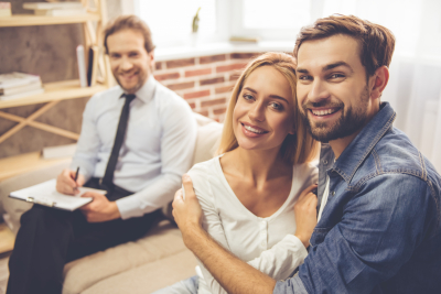 beautiful young couple is hugging and smiling while psychologist is making notes